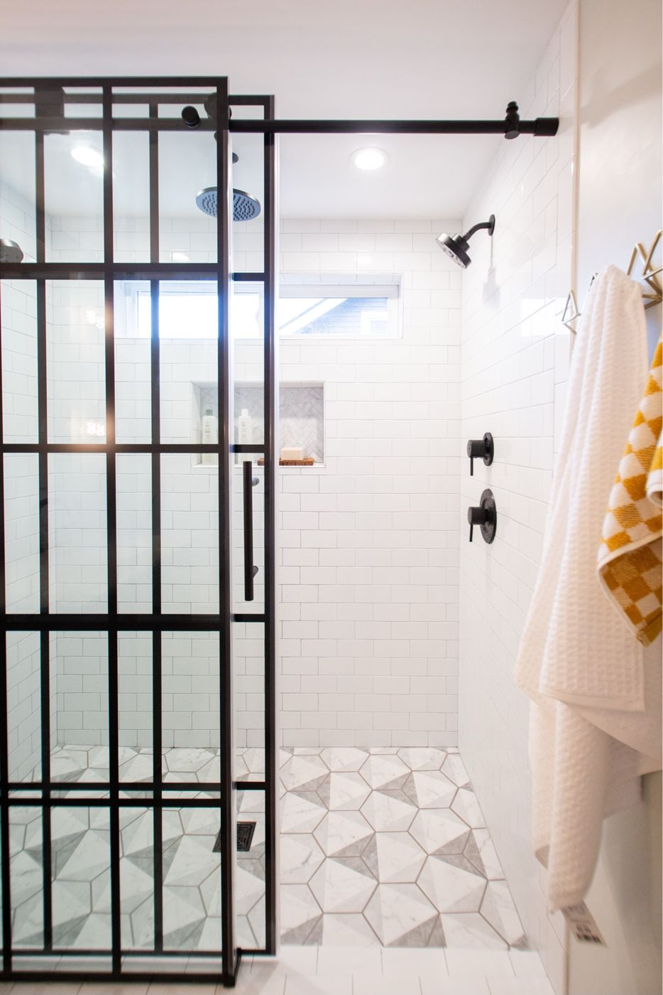 Walk-in shower with black grid glass door and subway tile